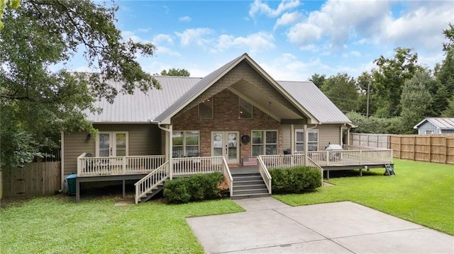 exterior space with metal roof, a front yard, a wooden deck, and fence