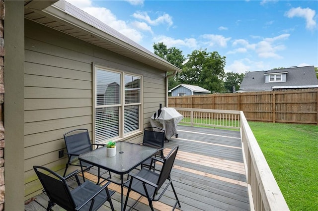 wooden terrace featuring outdoor dining space, fence, and a yard