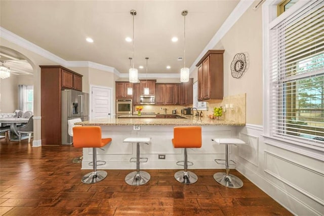 kitchen with light stone countertops, appliances with stainless steel finishes, a kitchen breakfast bar, and kitchen peninsula