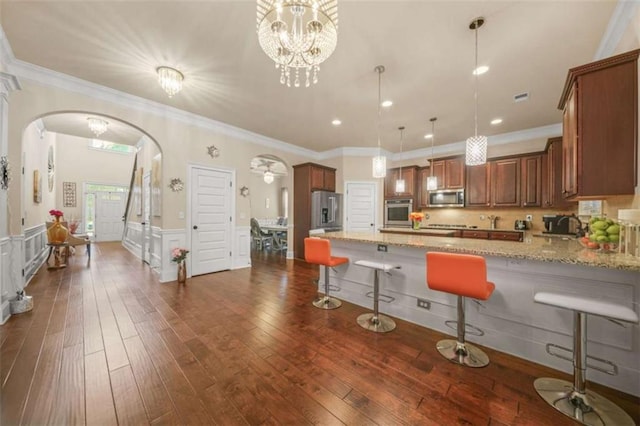 kitchen featuring hanging light fixtures, a kitchen breakfast bar, stainless steel appliances, light stone countertops, and dark hardwood / wood-style flooring