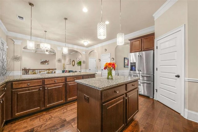 kitchen featuring pendant lighting, crown molding, high end fridge, a center island, and light stone countertops