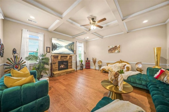 living room with coffered ceiling, a stone fireplace, hardwood / wood-style floors, and beam ceiling