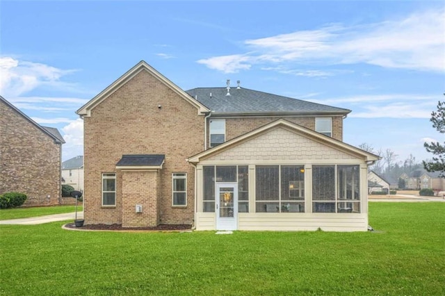 rear view of house featuring a sunroom and a lawn