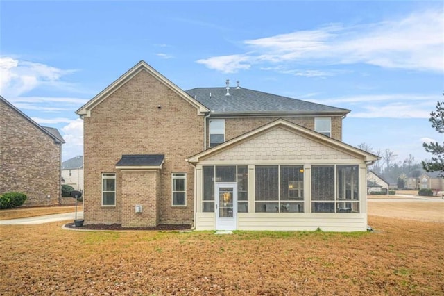 rear view of house featuring a sunroom and a lawn