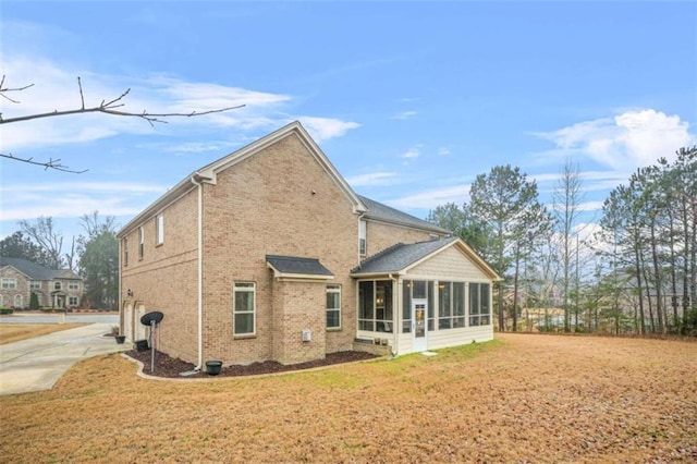 rear view of house featuring a yard and a sunroom