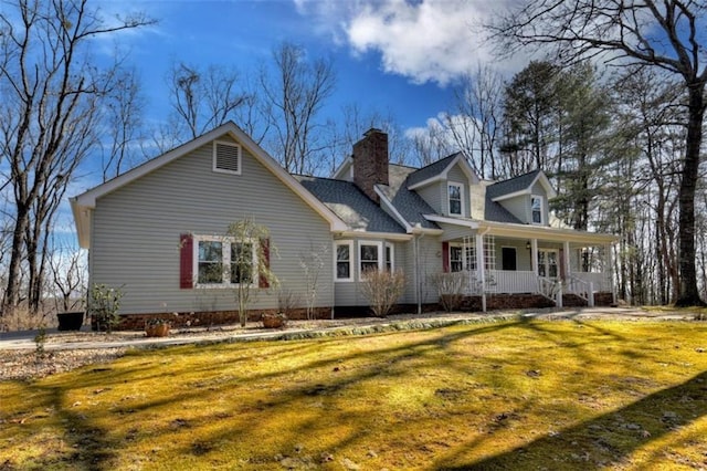 exterior space featuring a porch, a lawn, and a chimney