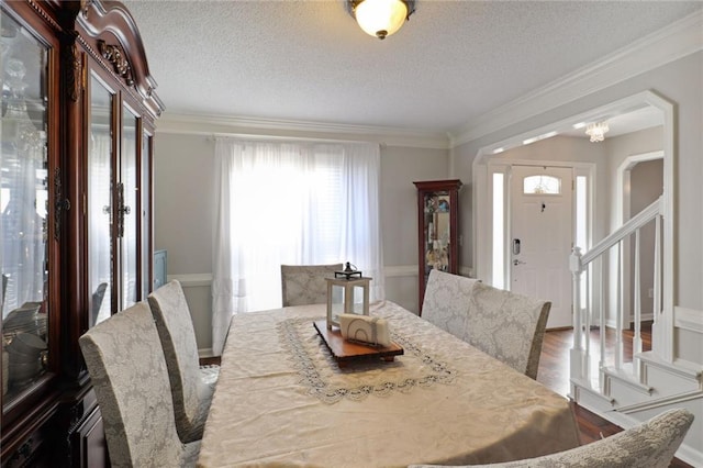 dining room featuring a notable chandelier, hardwood / wood-style flooring, ornamental molding, and a textured ceiling