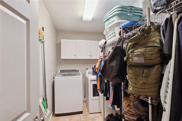 laundry area featuring washer and clothes dryer, cabinets, a textured ceiling, and light tile patterned flooring