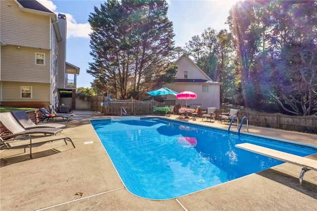 view of pool with a diving board and a patio area