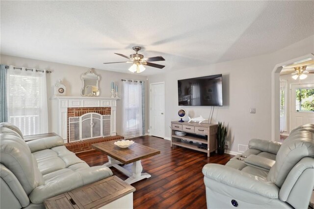 living room featuring ceiling fan, a fireplace, and dark hardwood / wood-style flooring