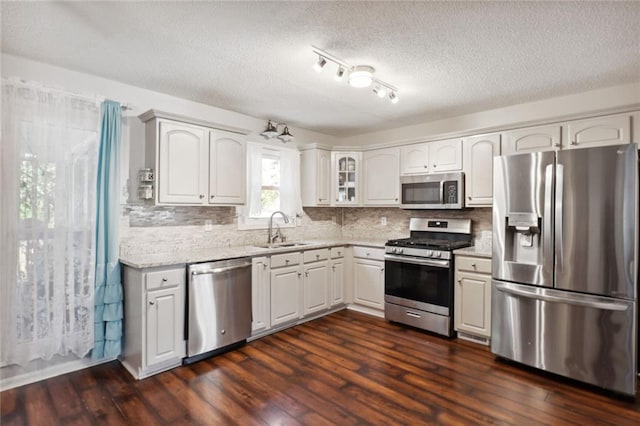 kitchen featuring sink, a textured ceiling, white cabinetry, stainless steel appliances, and dark hardwood / wood-style floors