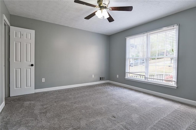 carpeted empty room with a ceiling fan, a textured ceiling, baseboards, and visible vents