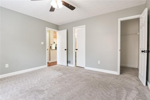 unfurnished bedroom featuring a spacious closet, carpet flooring, a closet, and baseboards
