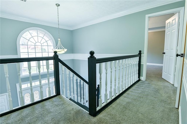 hallway featuring baseboards, an upstairs landing, crown molding, and carpet