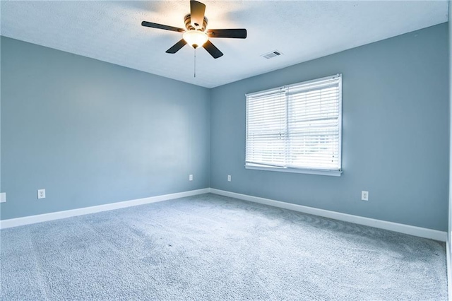 carpeted empty room with baseboards, a textured ceiling, ceiling fan, and visible vents
