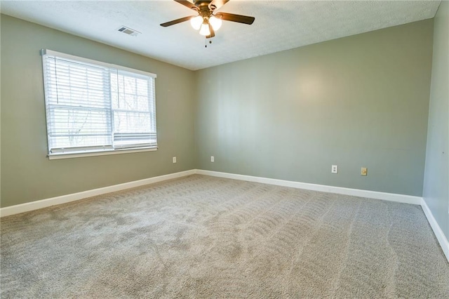 carpeted empty room featuring a textured ceiling, visible vents, baseboards, and a ceiling fan