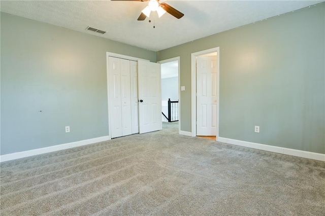 unfurnished bedroom with a closet, a textured ceiling, visible vents, carpet, and baseboards