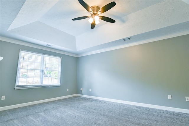 carpeted empty room featuring baseboards, visible vents, a textured ceiling, and a raised ceiling