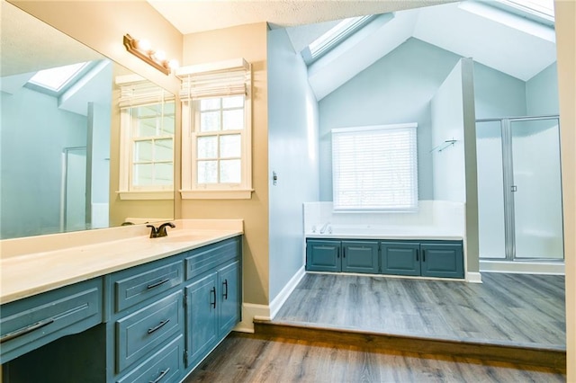 full bath featuring vanity, lofted ceiling with skylight, a shower stall, a garden tub, and wood finished floors