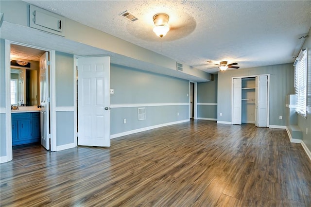 interior space featuring dark wood-type flooring, a textured ceiling, ceiling fan, and baseboards