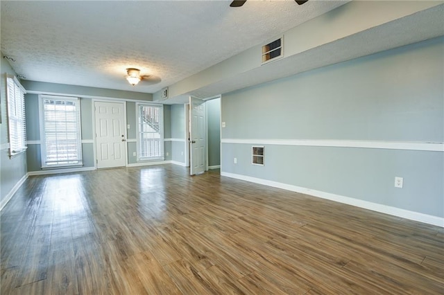 unfurnished room featuring baseboards, wood finished floors, ceiling fan, and a textured ceiling