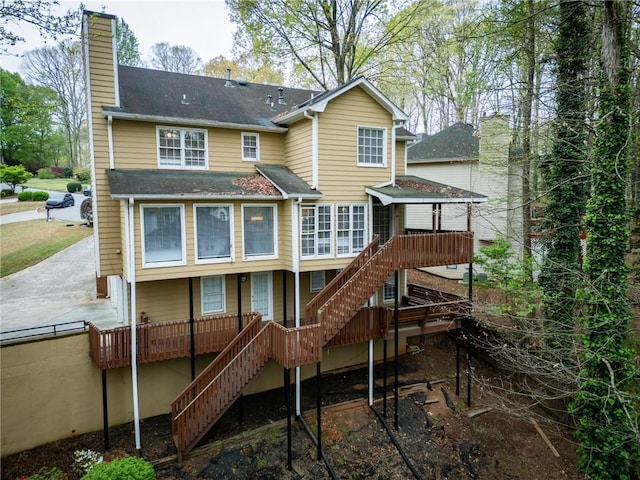 back of property featuring a shingled roof, stairs, and a chimney