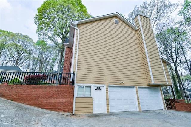 view of home's exterior featuring an attached garage, a chimney, and concrete driveway