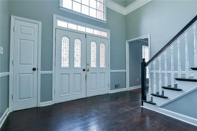 entrance foyer featuring a wealth of natural light, wood finished floors, a towering ceiling, and stairway