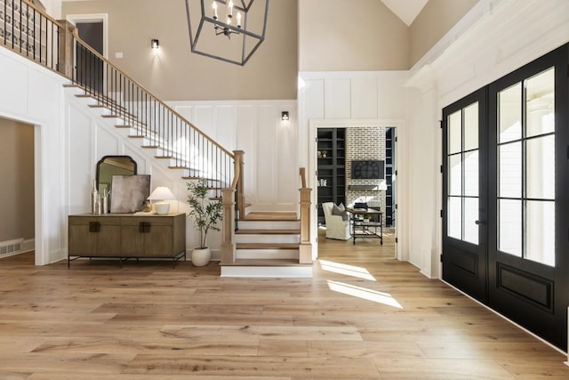 entryway featuring french doors, high vaulted ceiling, and light wood-type flooring