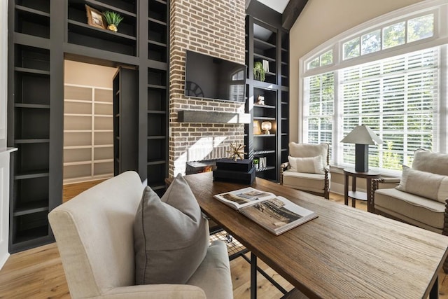 office with built in shelves, a fireplace, hardwood / wood-style floors, and a healthy amount of sunlight