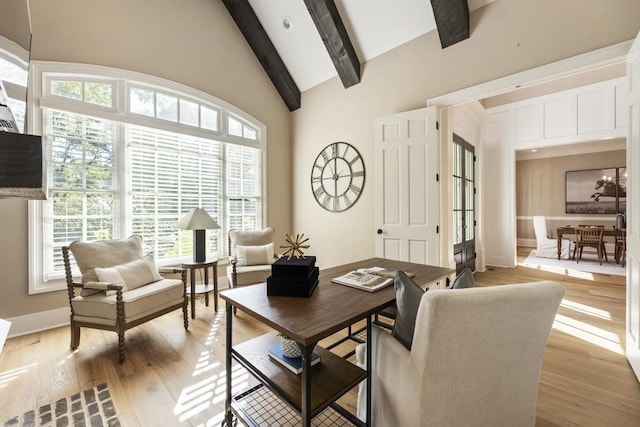 living room with beam ceiling, high vaulted ceiling, plenty of natural light, and light hardwood / wood-style floors