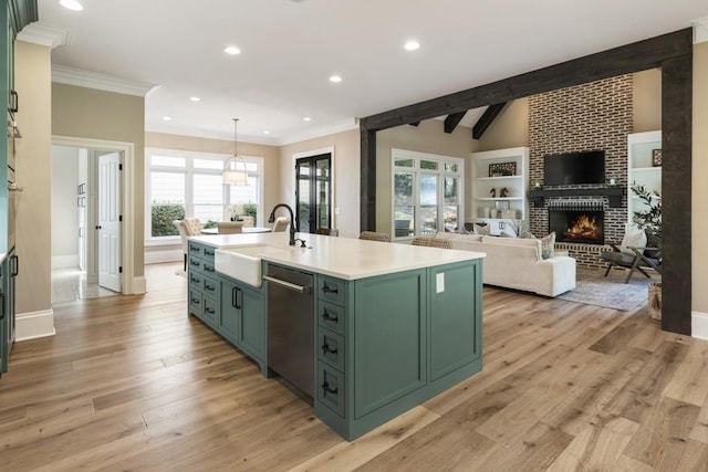 kitchen featuring a brick fireplace, a kitchen island with sink, light hardwood / wood-style flooring, sink, and dishwasher