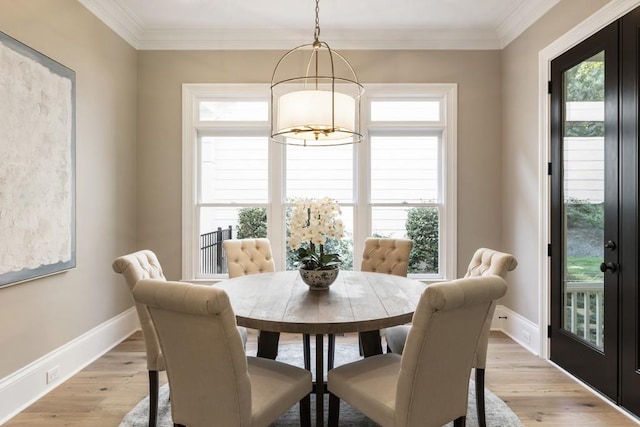 dining space with light hardwood / wood-style floors, crown molding, and a notable chandelier