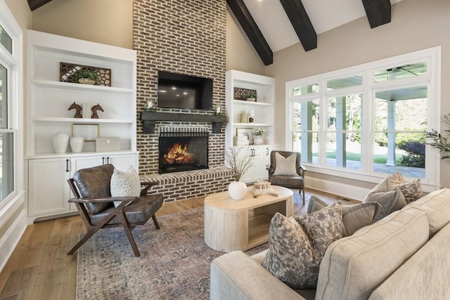 living room featuring light wood-type flooring, a fireplace, beam ceiling, and high vaulted ceiling