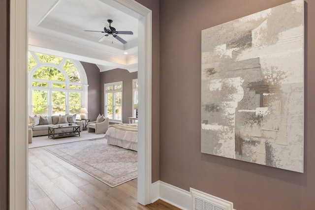 bedroom with crown molding, ceiling fan, a tray ceiling, and hardwood / wood-style floors