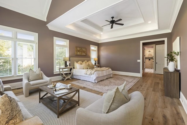 bedroom featuring ensuite bathroom, ceiling fan, a tray ceiling, hardwood / wood-style floors, and ornamental molding