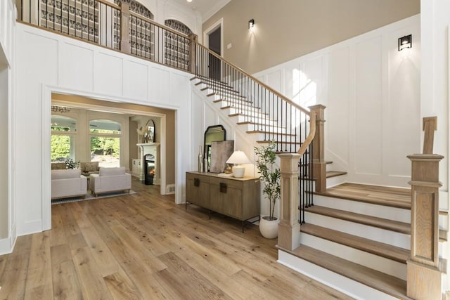 stairway with ornamental molding, a towering ceiling, and hardwood / wood-style floors