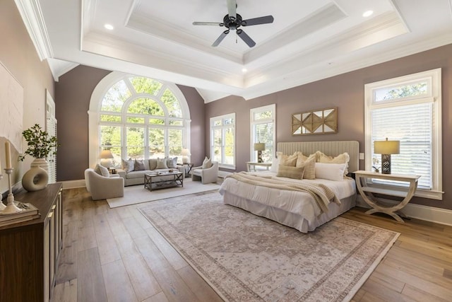 bedroom with crown molding, ceiling fan, a tray ceiling, and light hardwood / wood-style floors