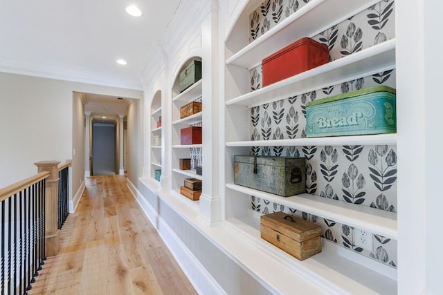 corridor with hardwood / wood-style flooring, crown molding, and built in features