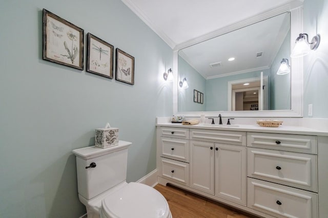 bathroom with wood-type flooring, ornamental molding, vanity, and toilet