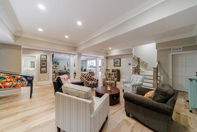 living room featuring ornate columns, light wood-type flooring, a raised ceiling, and ornamental molding