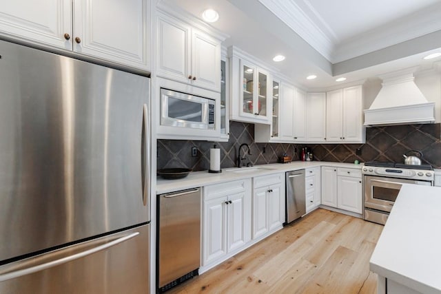 kitchen featuring white cabinets, appliances with stainless steel finishes, premium range hood, and sink