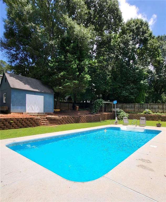 2913 Jordan Forest Trl, Lawrenceville, GA 30044 - view of pool with a storage unit, a patio, and view of wooded area