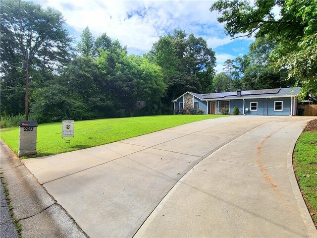 2913 Jordan Forest Trl, Lawrenceville, GA 30044 - view of front facade with driveway, roof mounted solar panels, and a front lawn