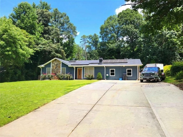 2913 Jordan Forest Trl, Lawrenceville, GA 30044 - ranch-style house featuring driveway, roof mounted solar panels, a front lawn, stone siding, and view of wooded area
