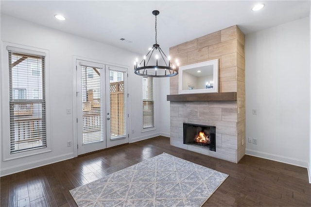 entryway featuring an inviting chandelier, dark hardwood / wood-style flooring, and a tiled fireplace