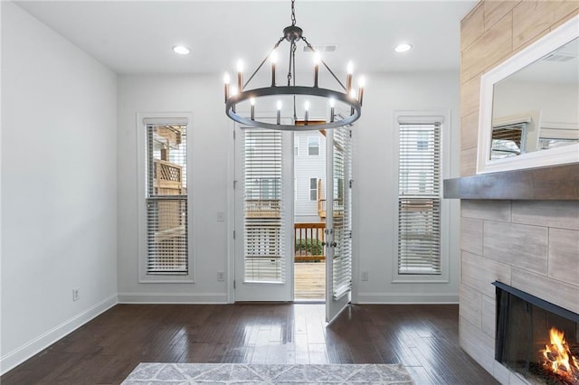 entryway featuring an inviting chandelier, a fireplace, and dark hardwood / wood-style flooring