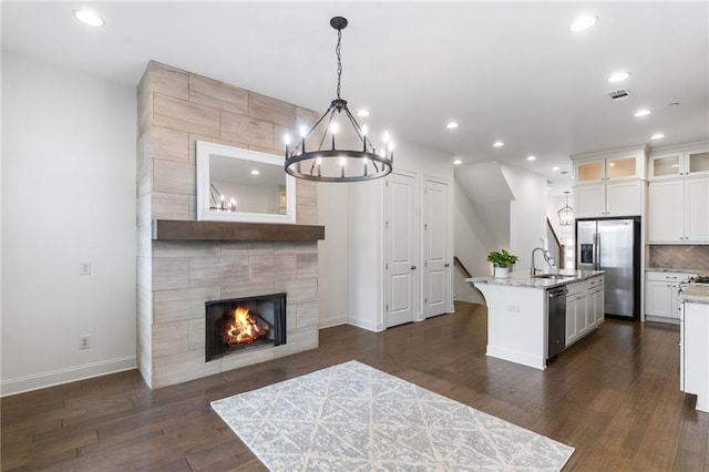 kitchen with a kitchen island with sink, light stone counters, white cabinetry, and appliances with stainless steel finishes