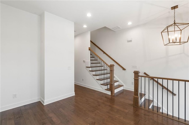 stairway featuring an inviting chandelier and wood-type flooring