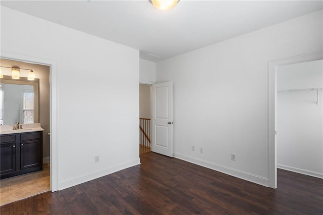 unfurnished bedroom with dark hardwood / wood-style floors, connected bathroom, sink, a spacious closet, and a closet